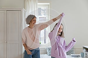 Happy mom and teen daughter dancing at home on weekend
