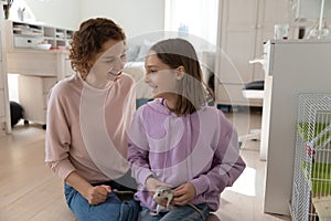 Happy mom and teen daughter play with domesticated mouse photo