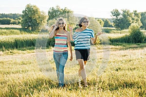 Happy mom and teen daughter smiling and talking. Walking in nature on a sunny summer day