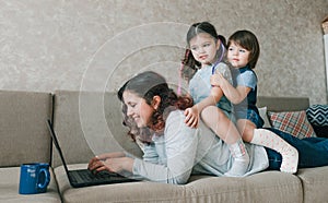 a happy mom tries to work and play with her kids at the same time.