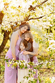 Happy mom and two daughters in a blossoming spring garden. parental love.