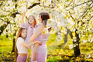 Happy mom and two daughters in a blossoming spring garden. parental love.