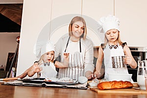 Happy mom and two daughters standing together in kitchen prepare and ready to learn how to make bakery. Idea for family