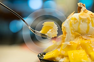 Happy moment with bingsu mango. Spoon scooping korean dessert with mango.