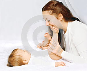 Happy moment mother playing with baby in bed