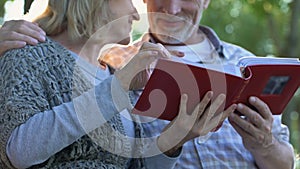 Happy moments, adult parents admiring photos in family album remembering youth