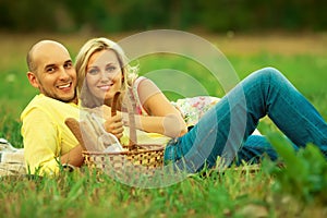 Happy moments of new family concept. Portrait of beautiful young couple having picnic in countryside. Smiling man and woman in tre