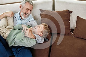 Happy moments. Portrait of cheerful grandfather and excited grandson embracing and having fun while relaxing on a couch