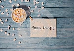 HAPPY MONDAY blue Monday concept text paper note with white cup of coffee and marshmallows on wooden background. The
