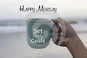 Happy Monday. Monday concept with business motivational text message on a coffee cup in hand - Set daily goals. Monday goal.