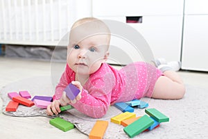 Happy 6 month baby girl plays wooden multicolored meccano photo