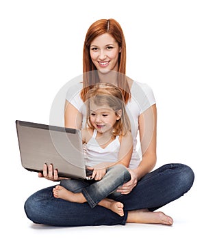 Happy mother with adorable little girl and laptop