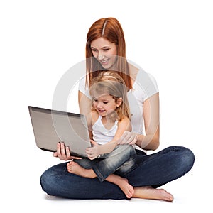 Happy mother with adorable little girl and laptop