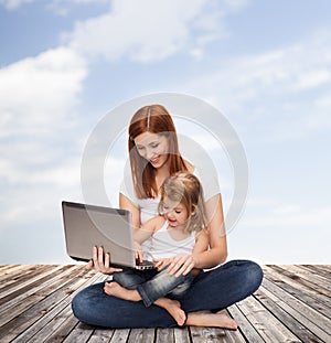 Happy mother with adorable little girl and laptop