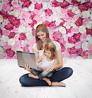 Happy mother with adorable little girl and laptop