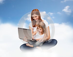 Happy mother with adorable little girl and laptop