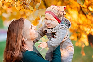 Happy mother and baby in autumn leaves