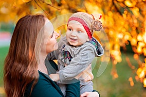 Happy mother and baby in autumn leaves