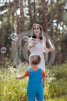 Happy mother baby bubble blower nature concept