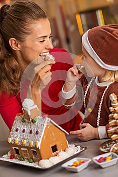 Happy mother and baby eating cookie in christmas kitchen