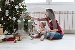 happy mother and baby girl decorating the Christmas tree