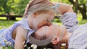 happy mother with baby girl lying on grass in park