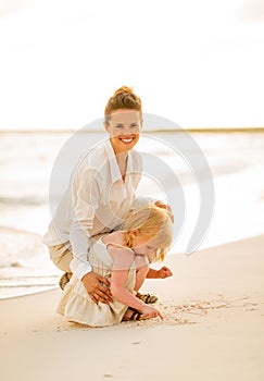 Happy mother and baby girl playing on the beach