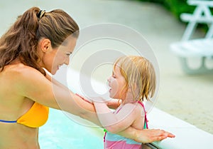 Happy mother and baby girl in swimming pool