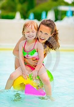 Happy mother and baby girl in swimming pool