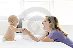 Happy mother with baby lying on bed at home