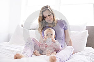 Happy mother with baby lying on bed at home