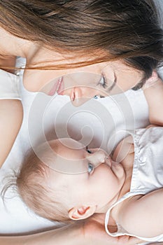 Happy mother with a baby lying on a white bed