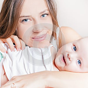 Happy mother with a baby lying on a white bed