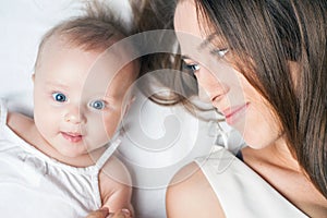 Happy mother with a baby lying on a white bed photo