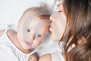 Happy mother with a baby lying on a white bed photo