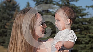 Happy mother and baby outdoors walking in summer day