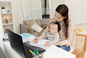 Happy mother with baby and papers working at home