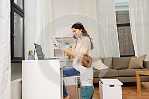 Happy mother with baby and papers working at home