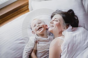 Happy mother and baby playing in bed. Happy family concept.