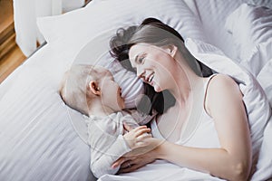 Happy mother and baby playing in bed. Happy family concept.