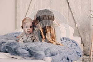 Happy mother and baby playing at home in bedroom. Cozy family lifestyle