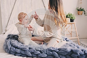 Happy mother and baby playing at home in bedroom. Cozy family lifestyle