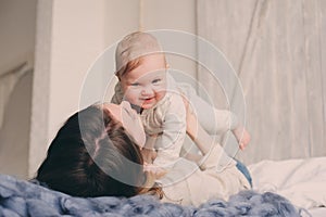 Happy mother and baby playing at home in bedroom. Cozy family lifestyle