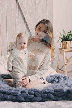 Happy mother and baby playing at home in bedroom. Cozy family lifestyle