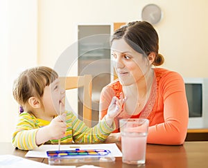 Happy mother and baby plays with watercolor