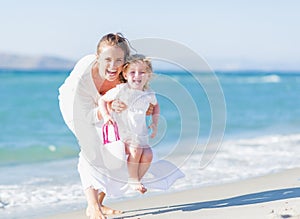 Happy mother and baby on sea shore having fun