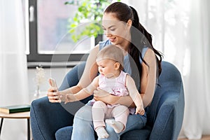 Happy mother and baby with smartphone at home