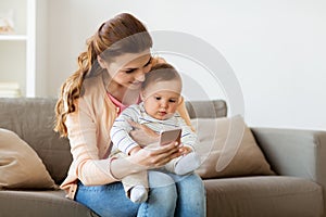 Happy mother with baby and smartphone at home
