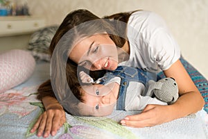 Happy mother in bed with her baby. Portrait of a beautiful loving mother playing first games with her baby in the bedroom