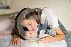 Happy mother in bed with her baby. Portrait of a beautiful loving mother playing first games with her baby in the bedroom